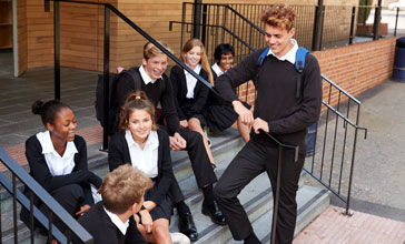 Group of teenage students in uniform outside school